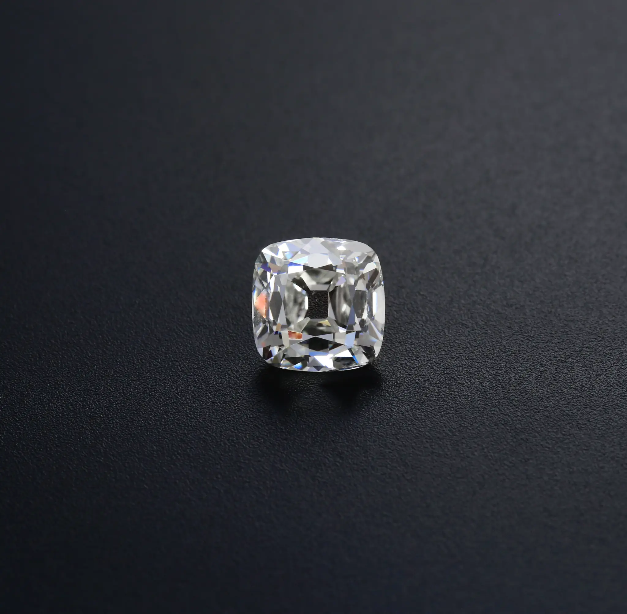 4.02 Ct. K SI1 Old Mine Cushion photographed on textured charcoal, showing broad facets and an open culet