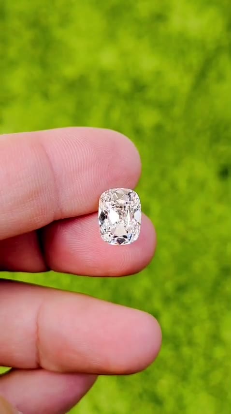 5.03 Ct. F VS1 Old Mine Cushion resting loose on a hand, showing its long cushion outline